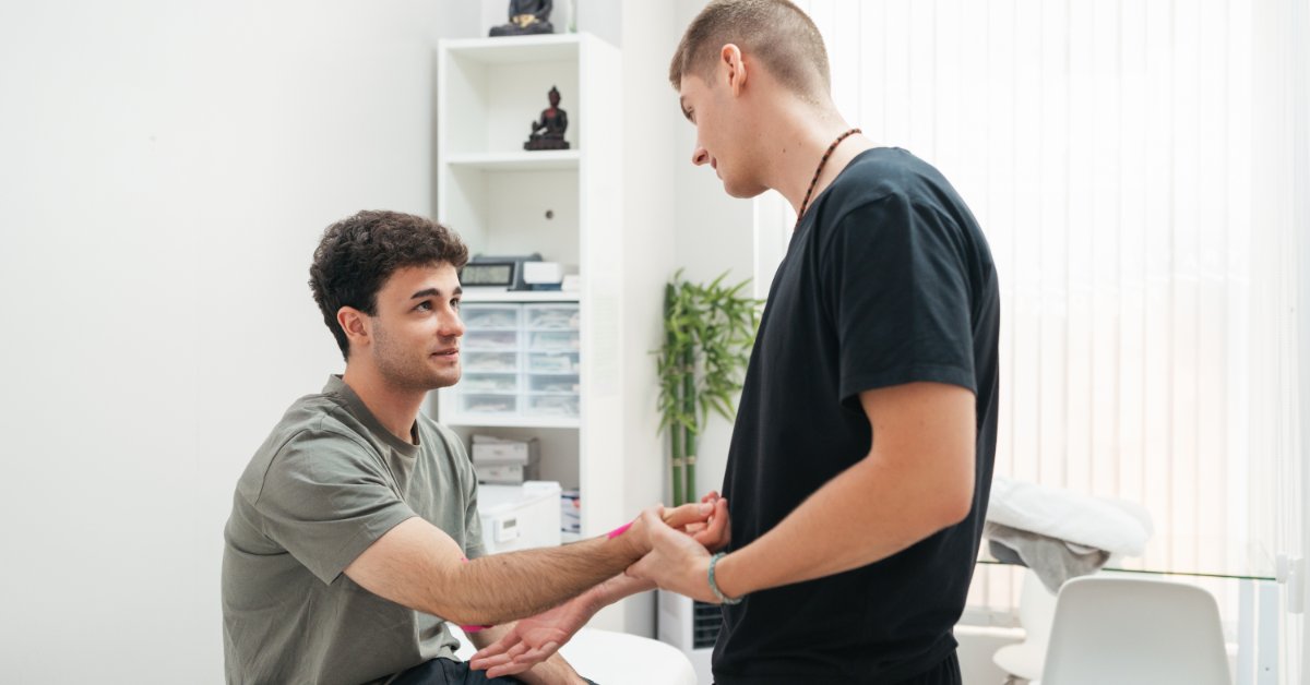 A healthcare professional evaluates an active adult's arm during a physical assessment in a clinical setting.