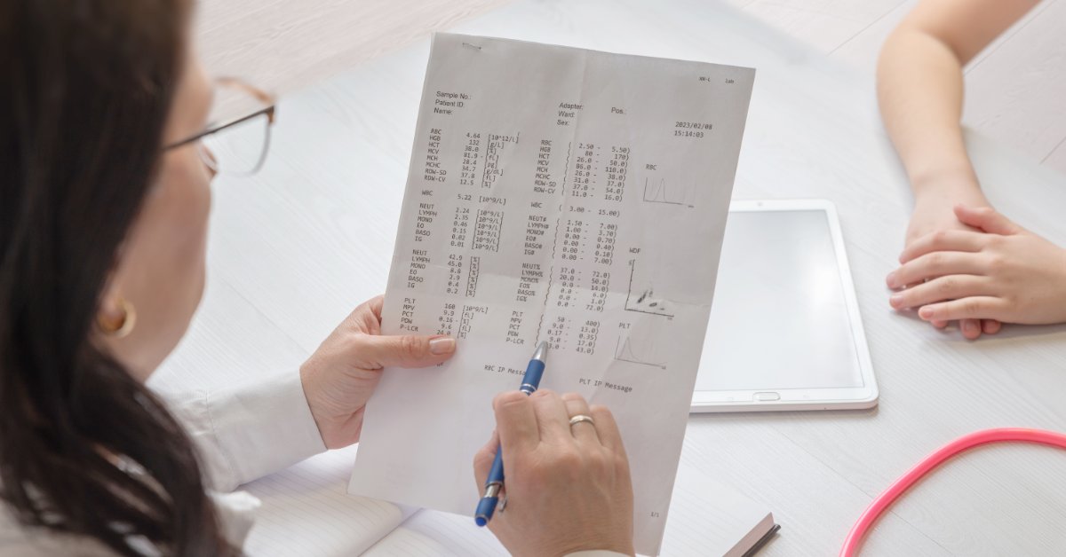 A physician reviews medical information with a patient while discussing details during a clinical consultation.