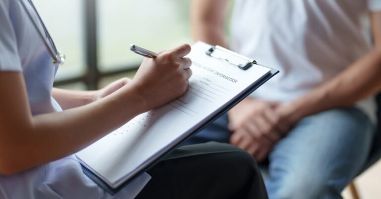 A physician takes notes while speaking with a patient during a personalized healthcare consultation.
