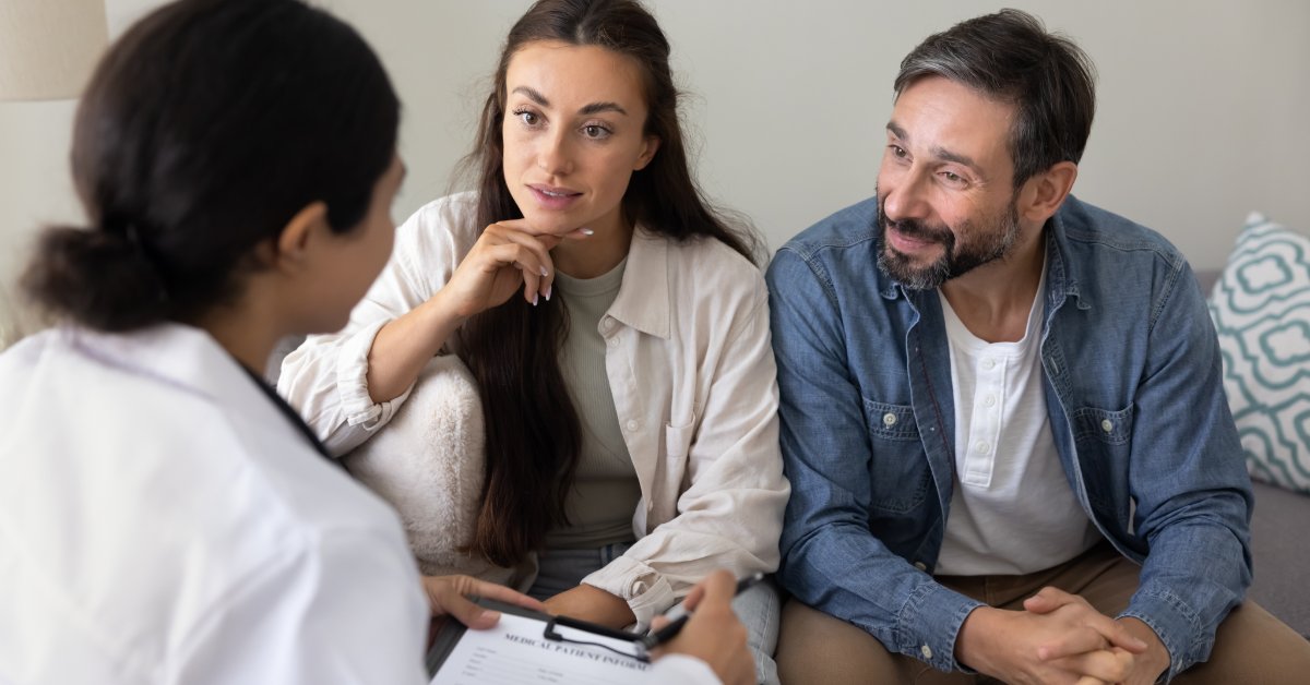 A couple speaks with a healthcare professional during a consultation about their health and wellness goals.