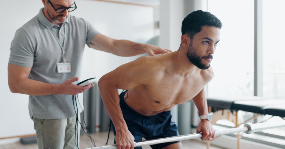A sports medicine provider observes an athlete performing a supported upper-body exercise during a movement assessment.